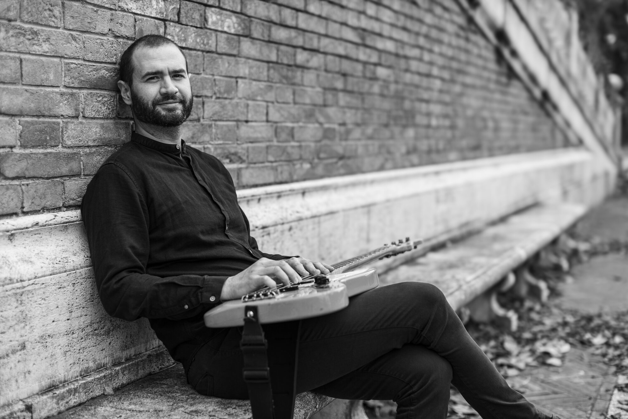 Giuseppe Vitale seated on a stone bench with his bass