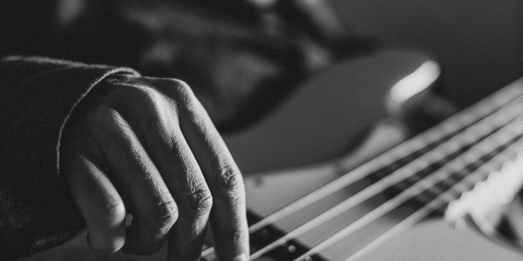 Hand on the strings of an electric bass